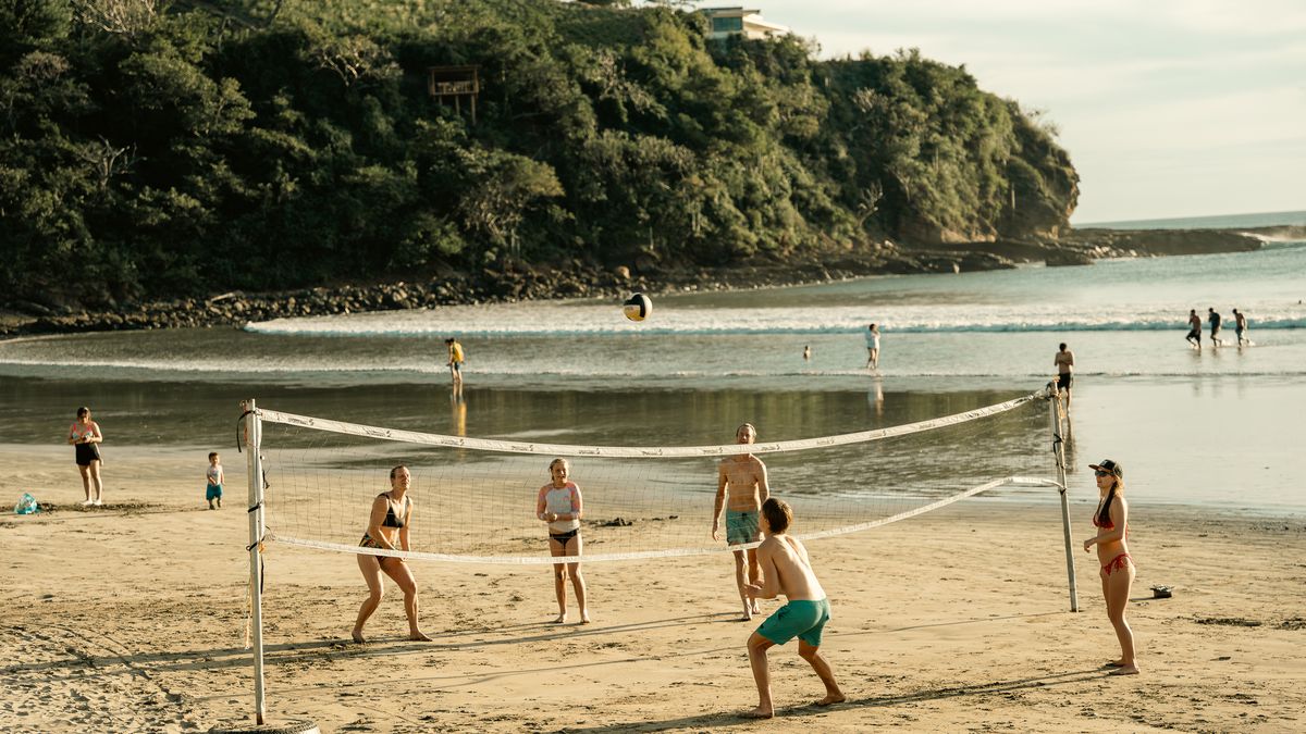 Friends play beach volleyball at low tide