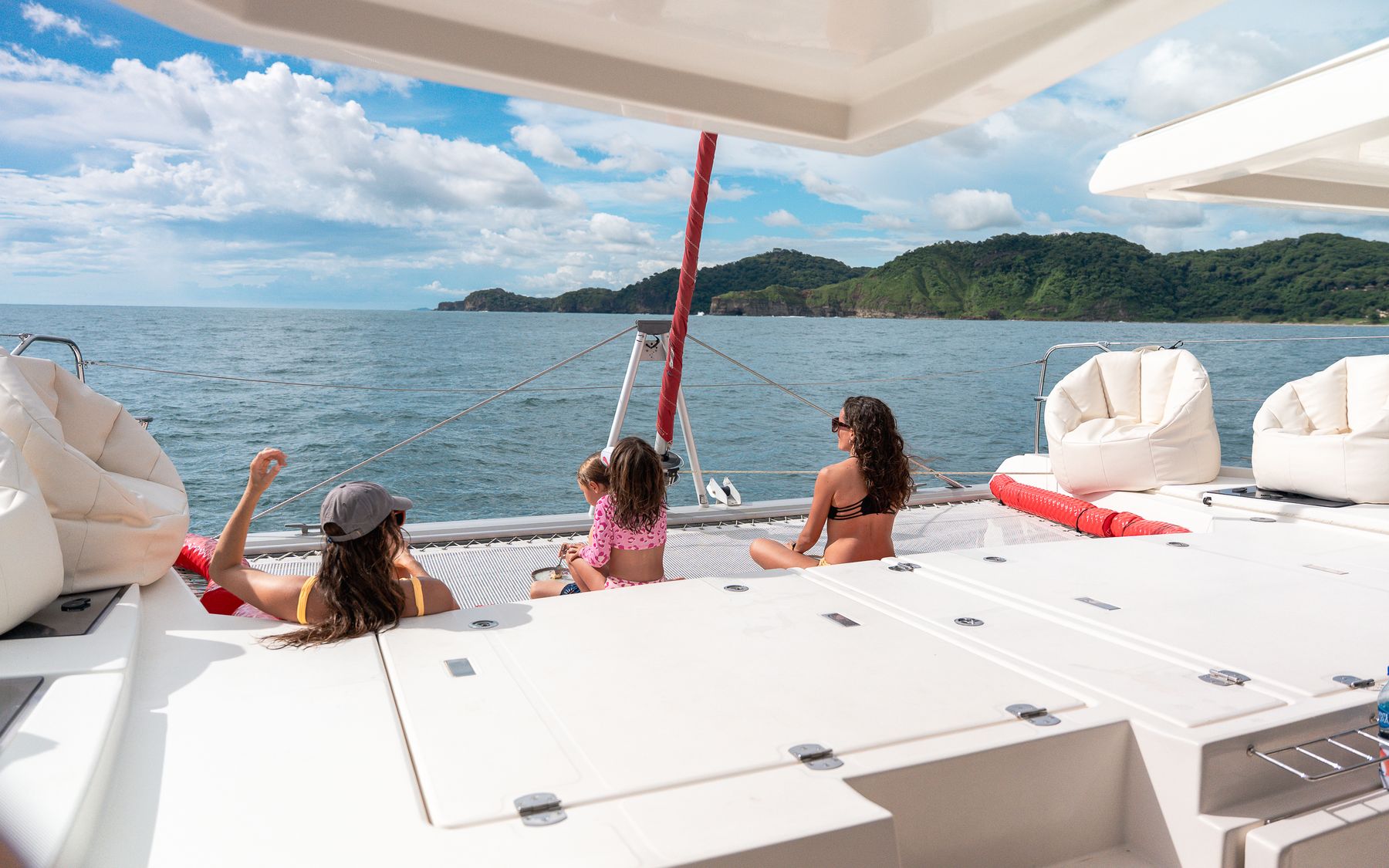 A mother and two girls relax on the deck of a catamaran in the bay